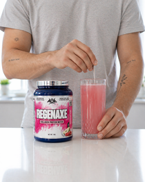 Person mixing a pink protein shake with a container labeled 'REGENAXE' on a white surface.